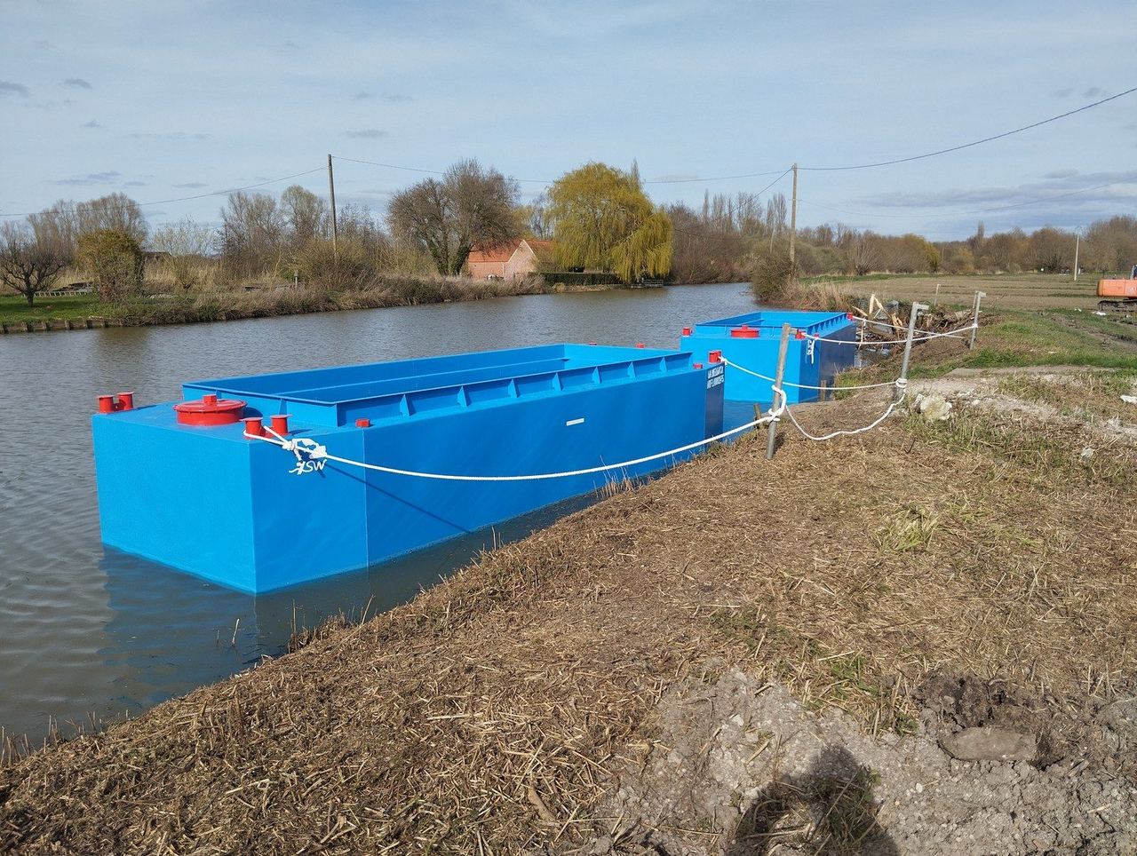 Barges acier livrées par Dragage Solutions, à flot le long de la berge
