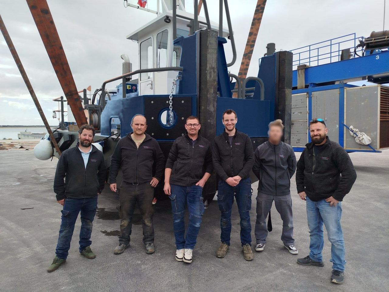 L'équipe Dragage Solutions devant un pousseur livré, sur l'élévateur du port