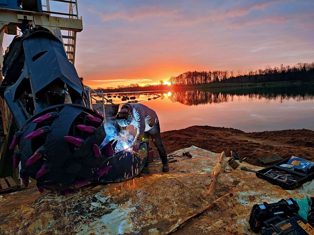 Soudeur Dragage Solutions sur un cutter au coucher du soleil