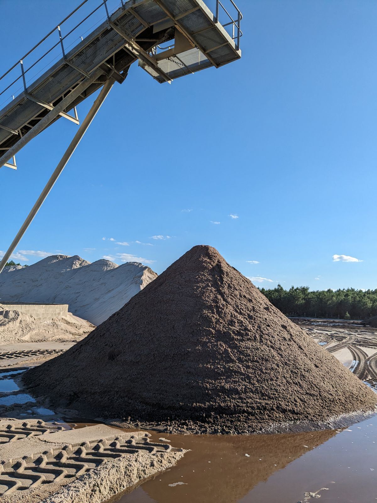 Tas de sable formé au pied d'un tapis stacker de sablière